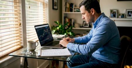 Man trading with AI system on home office laptop